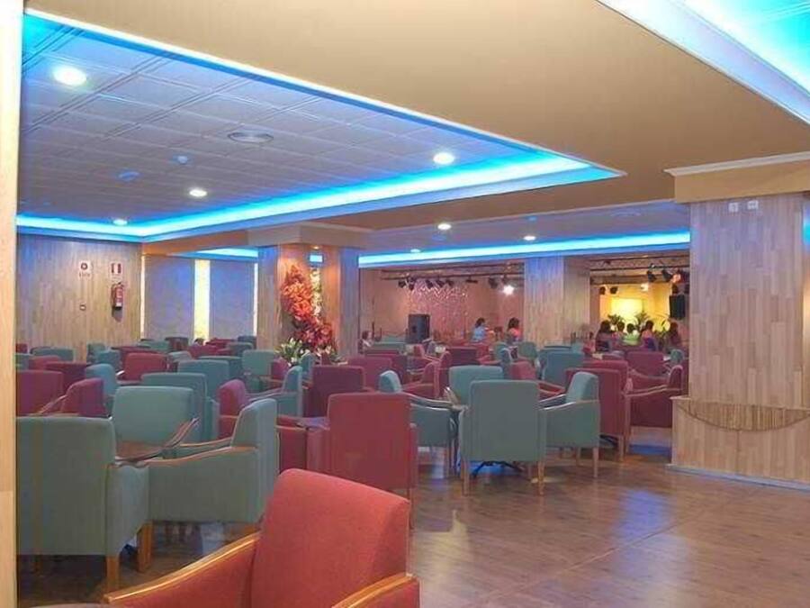 A hotel lobby with rows of seating, a reception area, and a decorative wall.