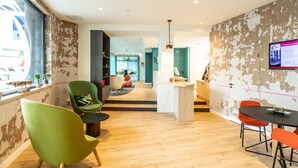 Een modern interieur met een houten vloer, een receptiebalie en een zithoek met stoelen.