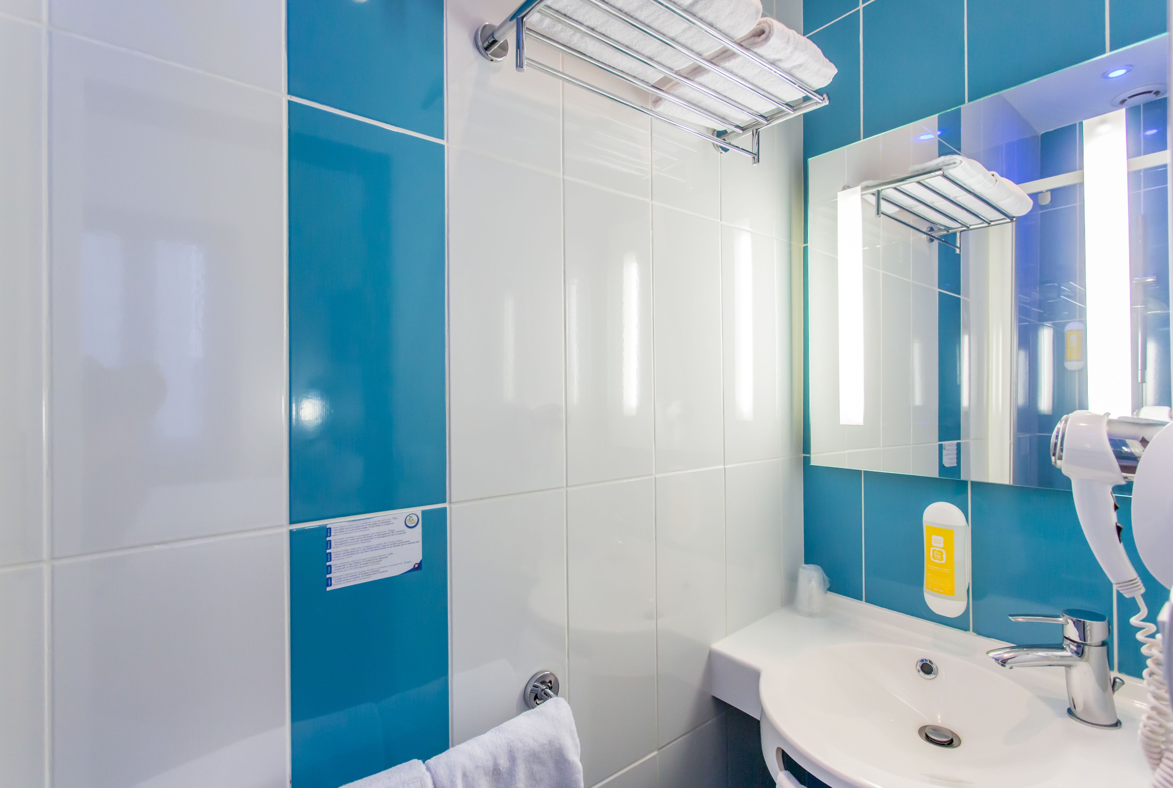 A bathroom with a white sink, a mirror, and a towel rack.