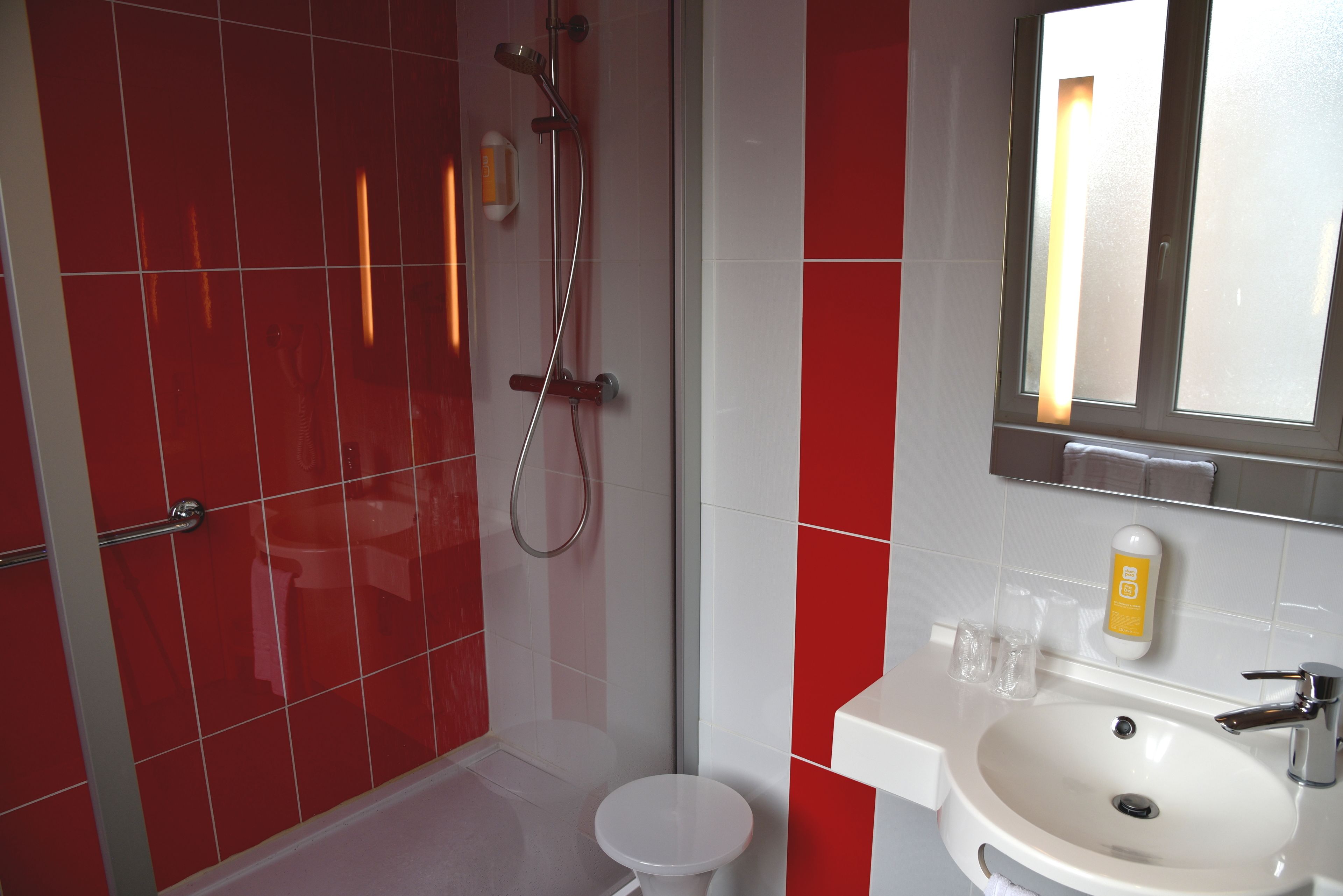 A bathroom with a shower, toilet, sink, and mirror.