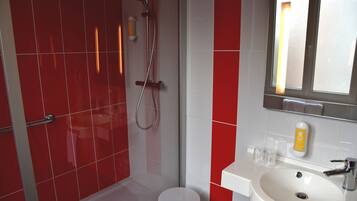 A bathroom with a shower, toilet, sink, and mirror.