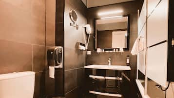 Un baño pequeño con inodoro, lavamanos, espejo y toallero.