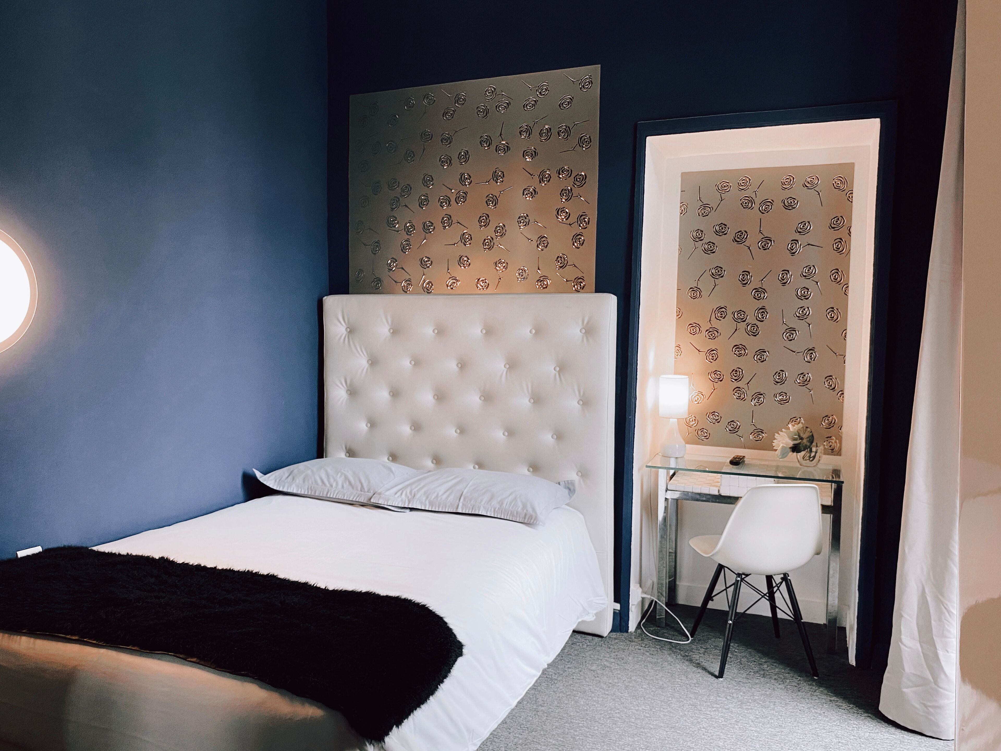 A bedroom with a large bed, a desk, and a chair.