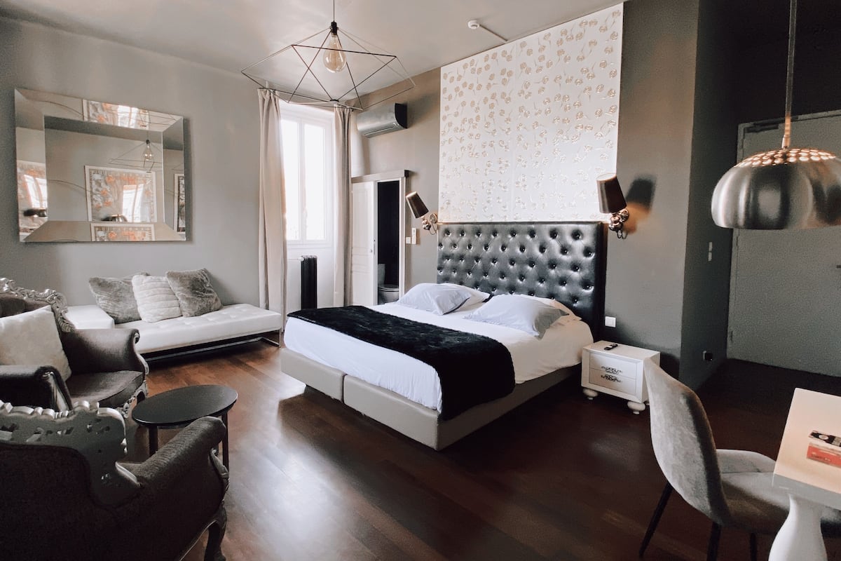 Una habitación de hotel moderna con una cama grande, un sofá, una mesa de comedor y un espejo.