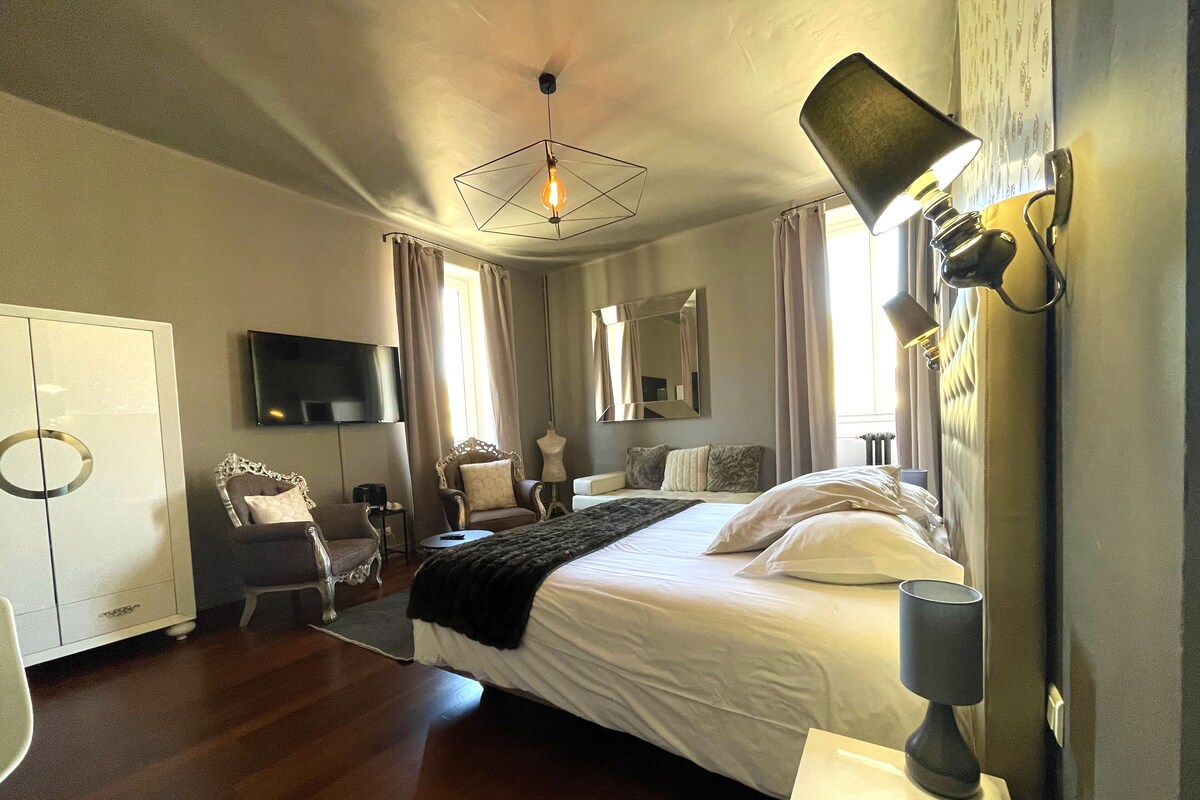A hotel room with a bed, bedside lamp, wardrobe, TV, and a mirror.