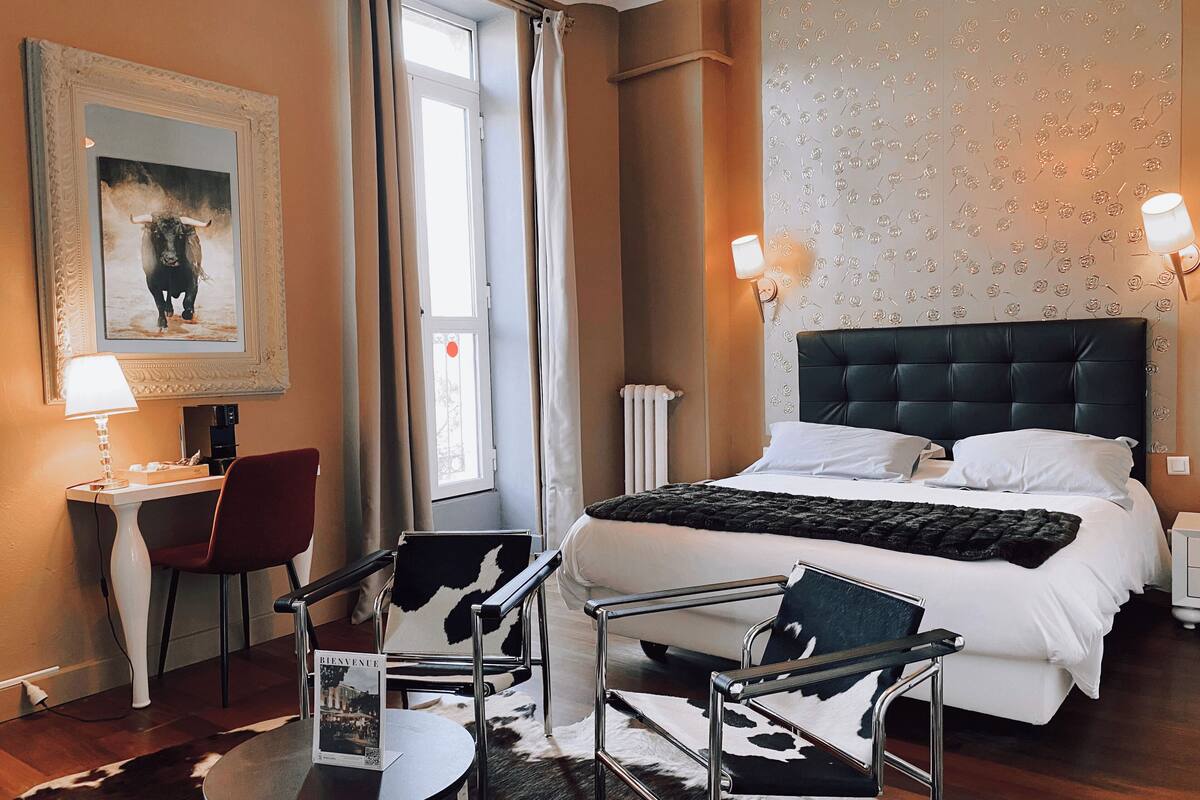 Habitación de hotel con cama, escritorio con silla, mesa y alfombra de cuero de vaca.