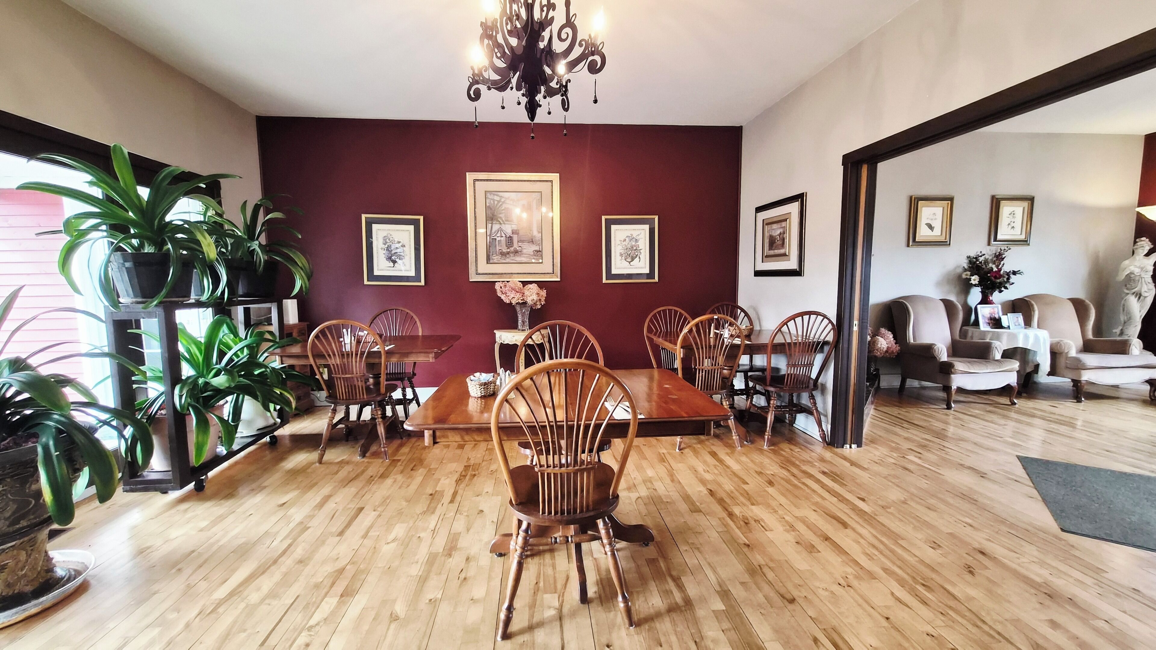 Un comedor con mobiliario de madera, una araña y cuadros en las paredes.