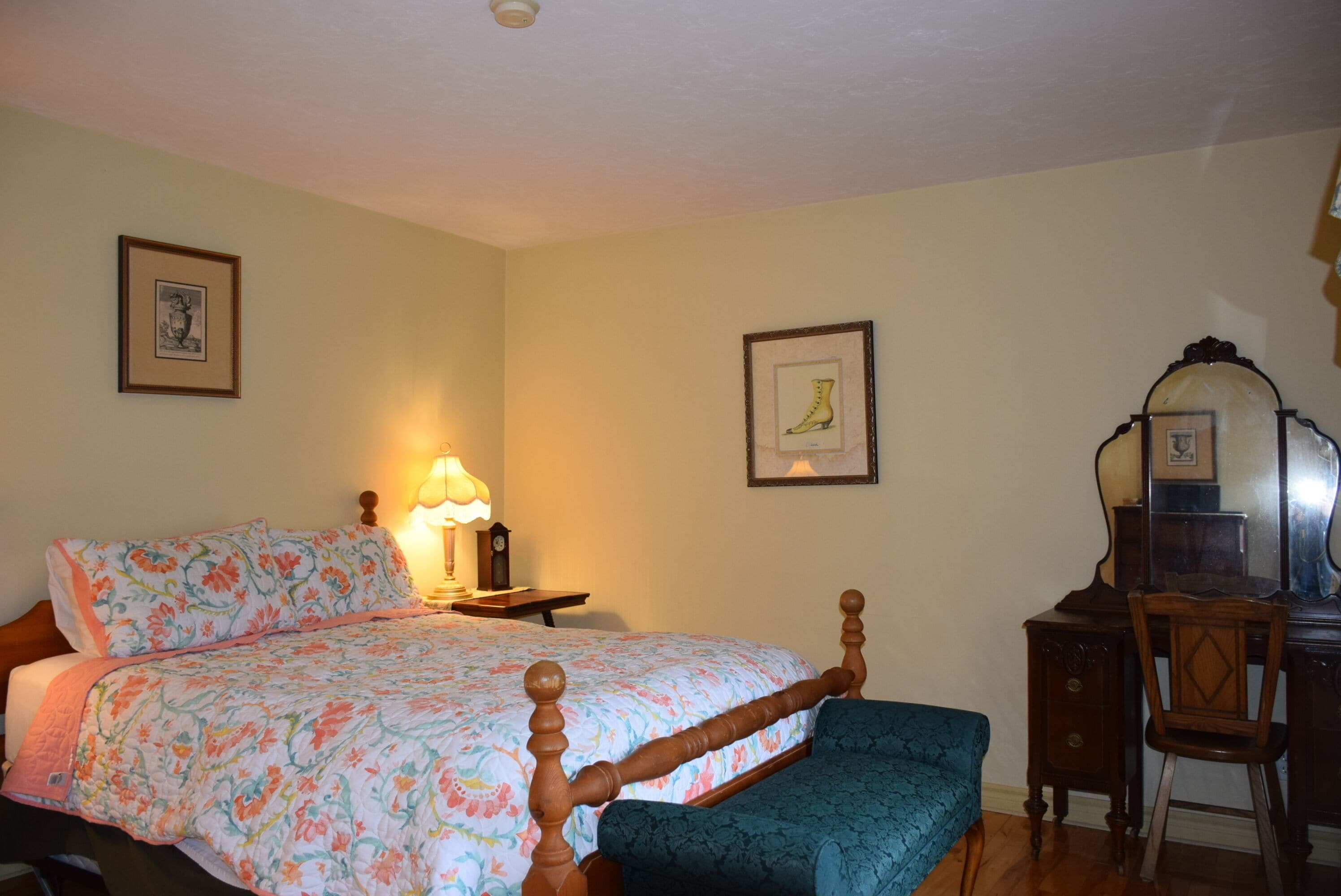 A bedroom with a bed, a chair, a desk, and a mirror.