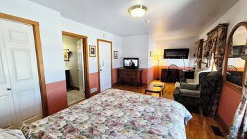 Een hotelkamer met een bed, een bureau, een stoel, een televisie en een spiegel.