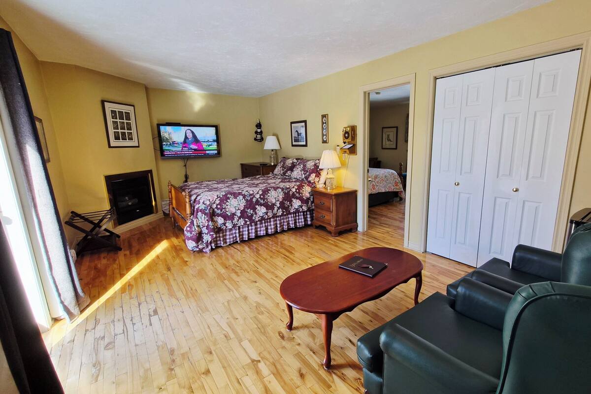 A room with a bed, a TV, a desk, a chair, and a door.