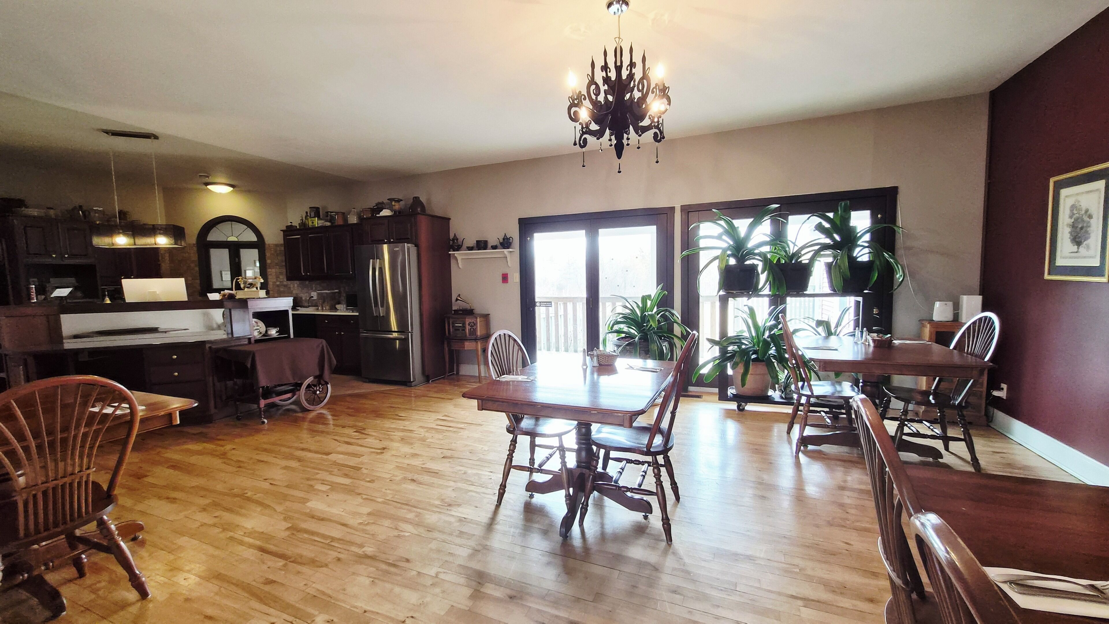 A spacious kitchen with a dining area, wooden flooring, and a chandelier.