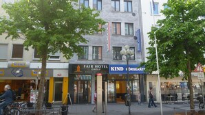Un edificio de varios pisos con un restaurante en la planta baja llamado 'Mr. Baker' y un hotel llamado 'Fair Hotel Group' con un letrero que dice 'Kind'.