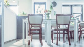 A modern kitchen with wooden chairs, a dining table, and a potted plant on the counter. - Fair Hotel Mönchengladbach (Moenchengladbach)
