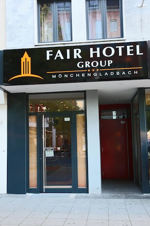 L'ingresso di un hotel con un cartello che recita 'FAIR HOTEL GROUP' e 'MÖNCHENGLADBACH'.