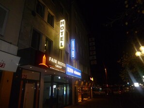 Un hôtel avec une enseigne bien visible indiquant « HÔTEL », une autre mentionnant « FAIR HOTEL GROUP » et une troisième, intitulée « KIND HÖRGENEITE », qui signale la présence d’un restaurant.
