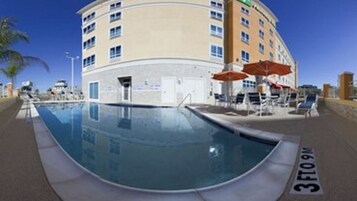 Un hotel con zona de piscina, incluyendo sillones de descanso y sombrillas.