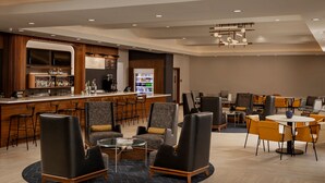 A modern hotel lobby with a bar area, seating arrangements, and a coffee machine. - Courtyard by Marriott Houston Kemah (Kemah)