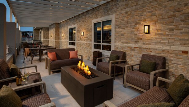 An outdoor patio area with a fire feature, seating, and a brick wall. - Courtyard by Marriott Houston Kemah (Kemah)