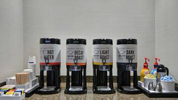 Una estación de café con cuatro dispensadores etiquetados: agua caliente, descafeinado, tueste claro y tueste oscuro.