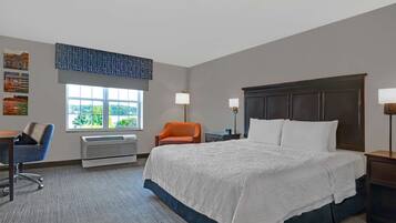 Habitación de hotel con una cama grande, un escritorio con silla, una ventana con vistas y un aire acondicionado instalado en la pared.