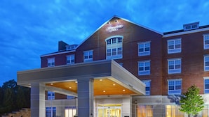 Um hotel Hampton Inn com fachada de tijolos, entrada coberta e área de acesso bem iluminada.