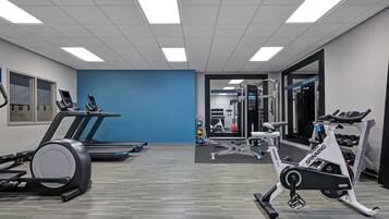 Une salle de sport équipée de tapis de course, d’un appareil elliptique et de machines de musculation.
