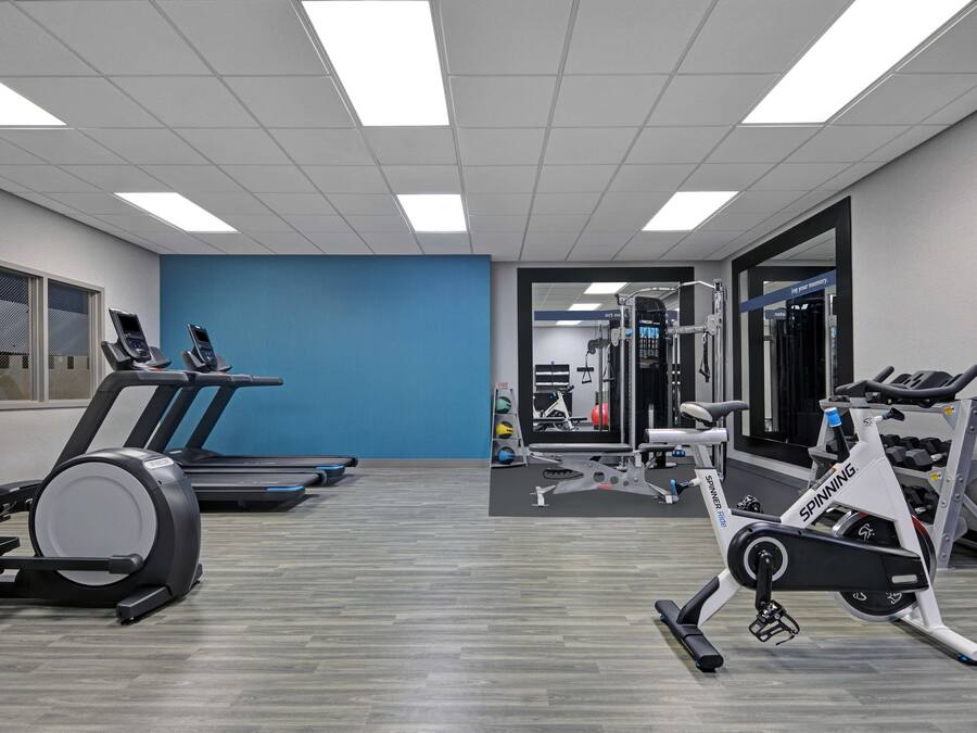 Une salle de sport équipée de tapis de course, d’un appareil elliptique et de machines de musculation.