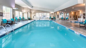 A swimming pool with clear blue water, surrounded by lounge chairs and a staircase leading to an upper level. - Residence Inn by Marriott Duluth (Duluth)