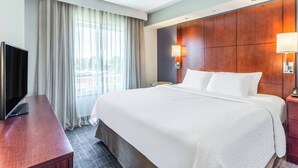 A hotel room with a large bed, a flat-screen TV, a wooden desk, and a window with curtains. - Residence Inn by Marriott Duluth (Duluth)