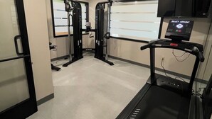 Un gimnasio con cinta de correr, máquinas de pesas y una pantalla de televisión.
