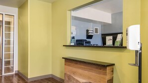 Una habitación con un escritorio de madera, un espejo, una impresora y un purificador de aire de pared.