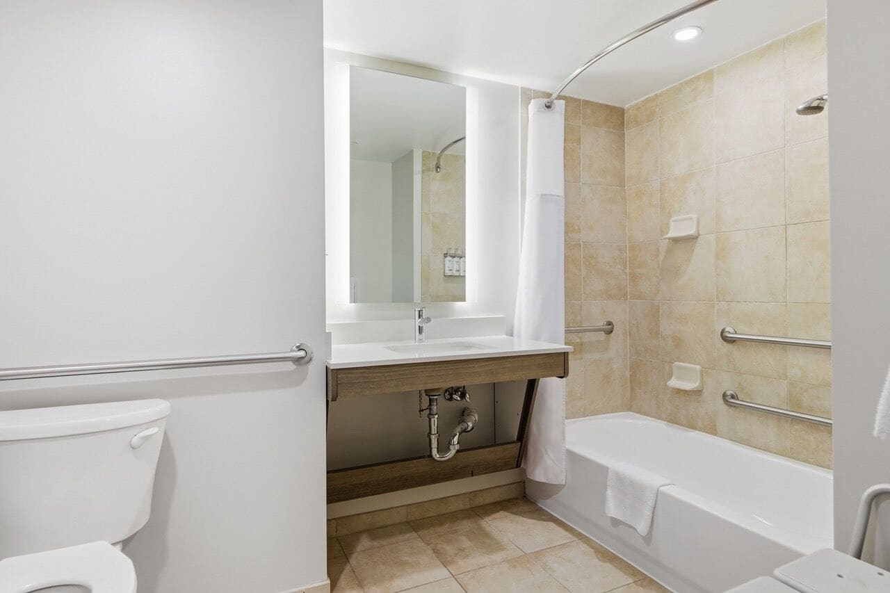 A modern bathroom with a toilet, sink, mirror, shower, and bathtub.