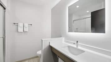 Un baño moderno con un lavabo blanco, un espejo y un perchero para toallas.