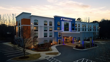 Un hotel Holiday Inn Express & Suites con un diseño moderno, que presenta una entrada destacada y un estacionamiento.