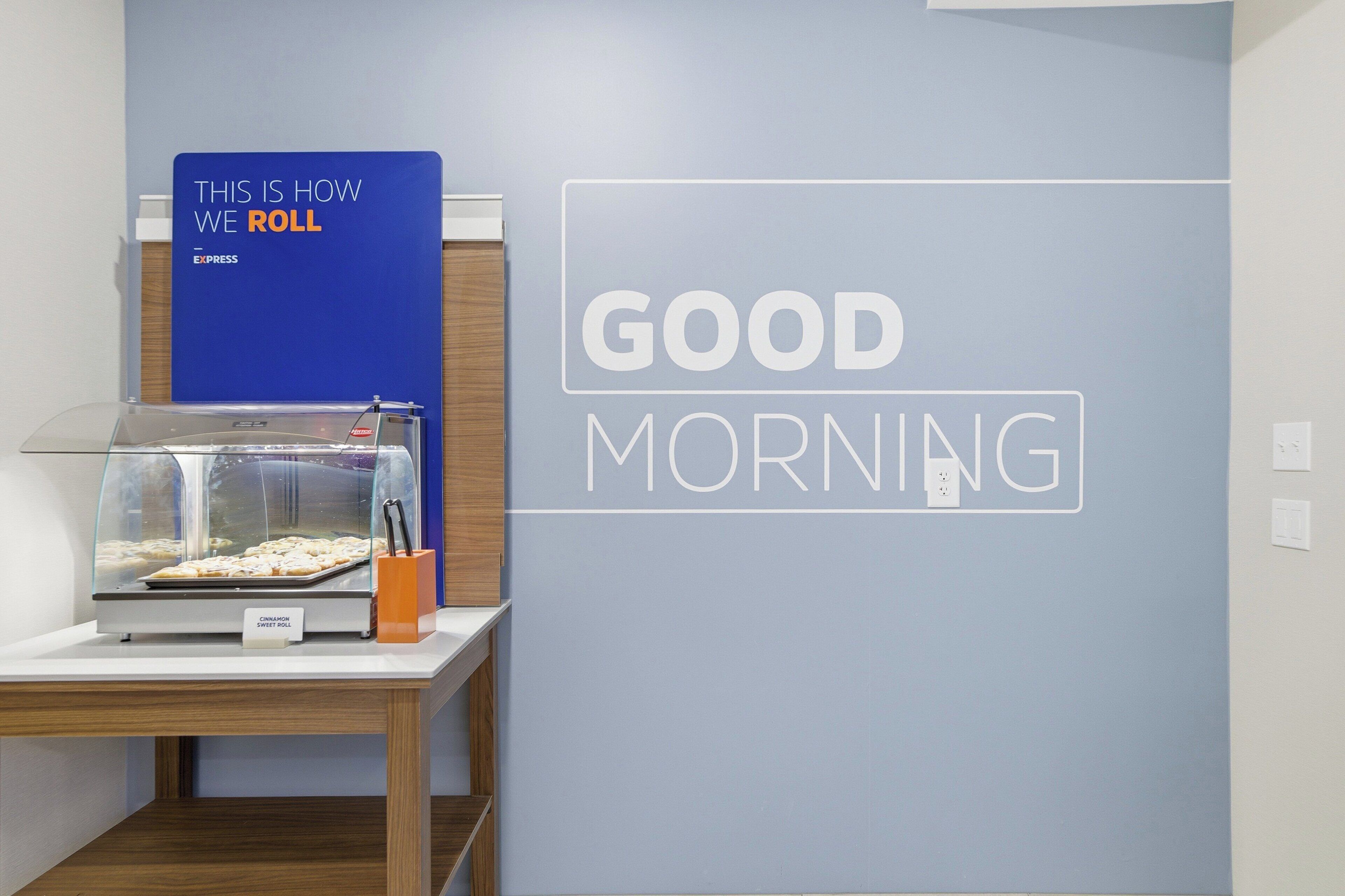 A breakfast display with a sign that reads "THIS IS HOW WE ROLL" and a wall sign saying "GOOD MORNING".