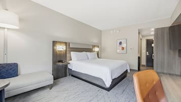 Een moderne hotelkamer met een bed, een bankje, een stoel en een bureau.