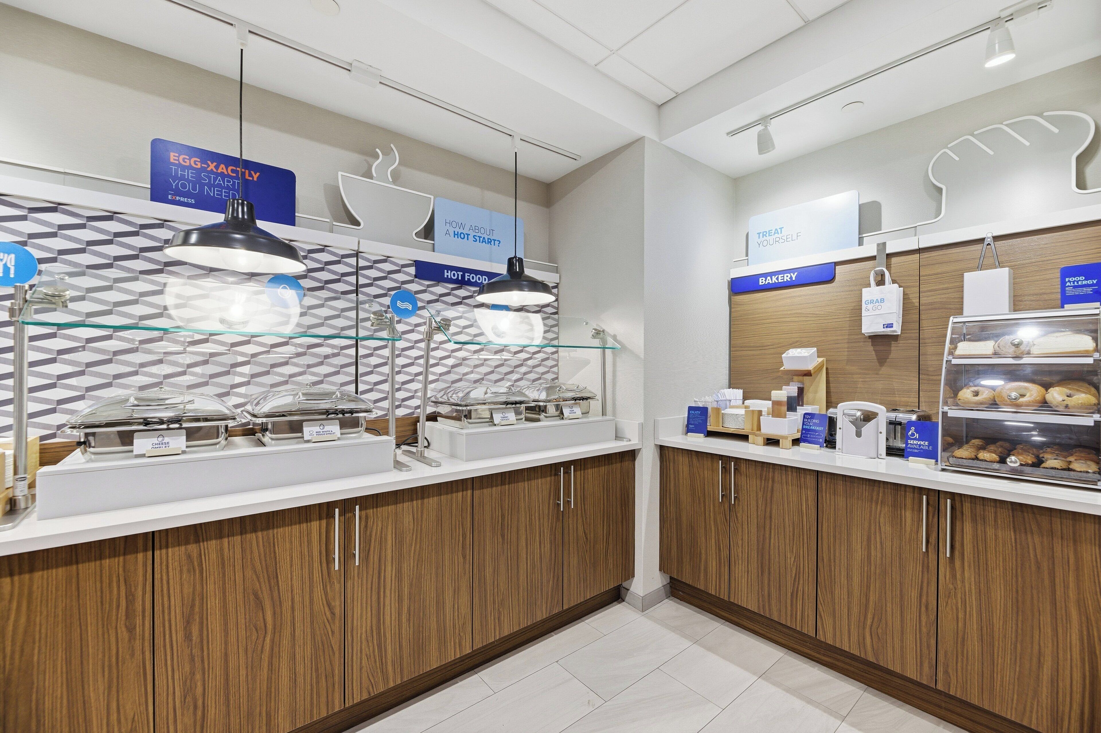 A breakfast area with a buffet setup, including hot food and bakery items.