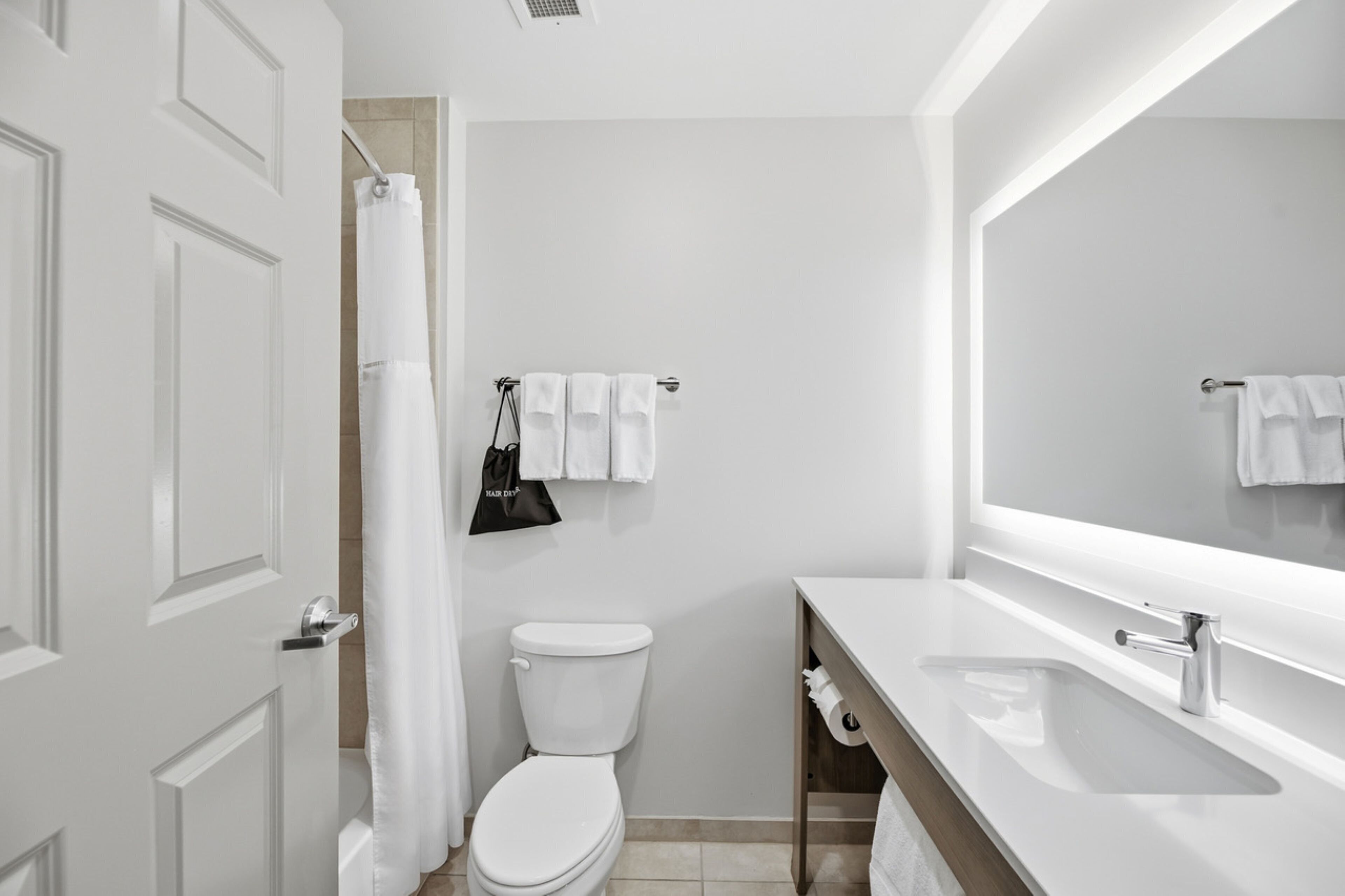 A modern bathroom with a toilet, a sink, a mirror, and a shower curtain.