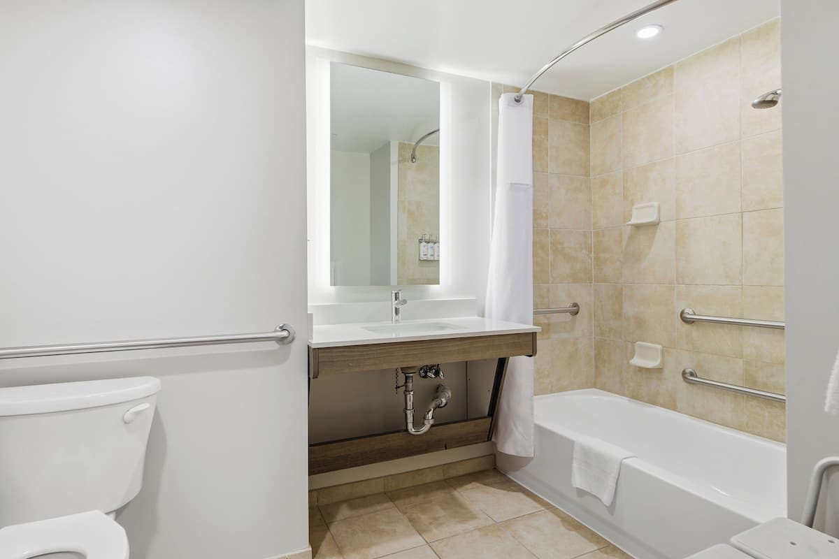 A modern bathroom with a toilet, sink, bathtub, and shower.