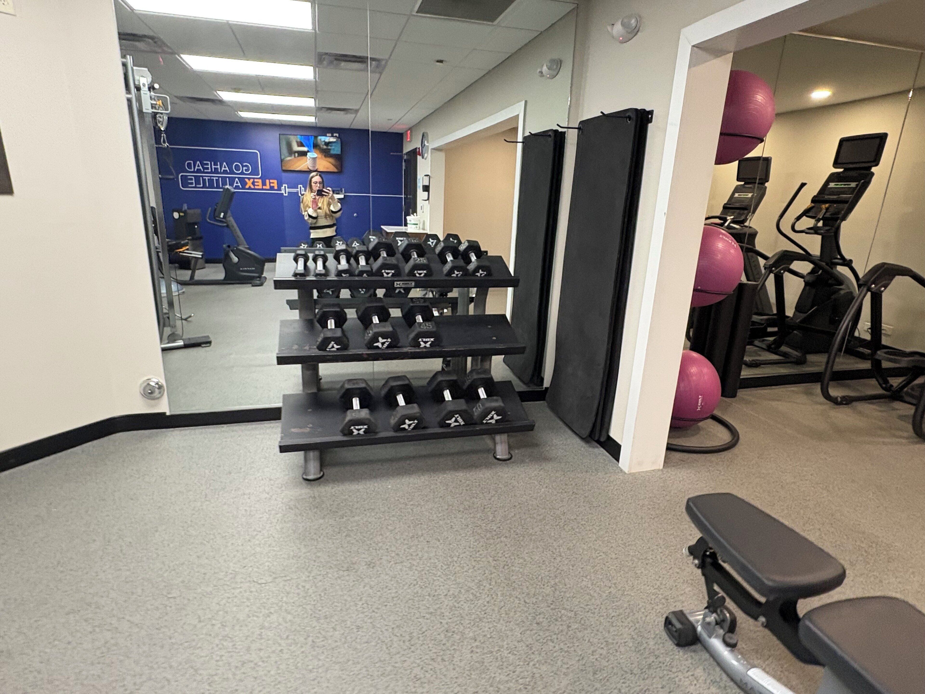 Un gimnasio con mancuernas, pelotas de ejercicio y cintas de correr.