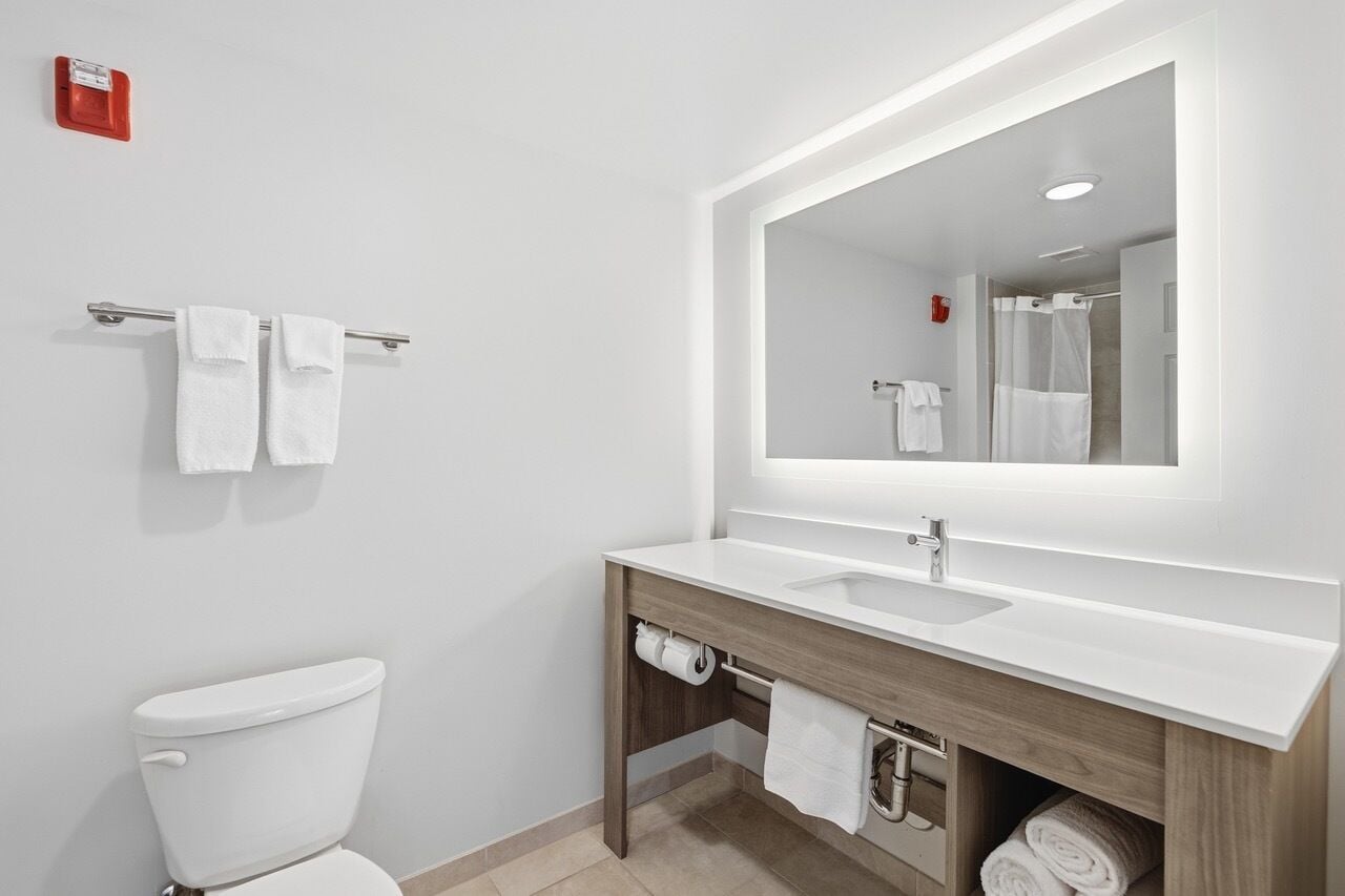 A modern bathroom with a white toilet, a sink with a mirror, and a towel rack.