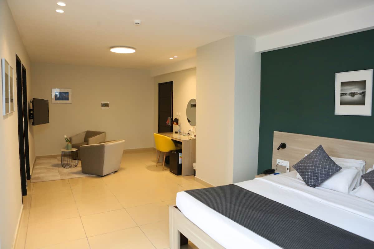 A hotel room with a bed, a desk, a chair, and a small table.