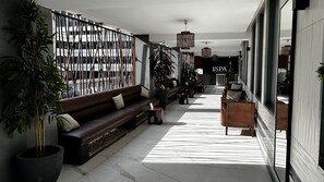 A modern indoor corridor with a sofa, chairs, and potted plants. - Ivotel Abidjan (Abidjan)