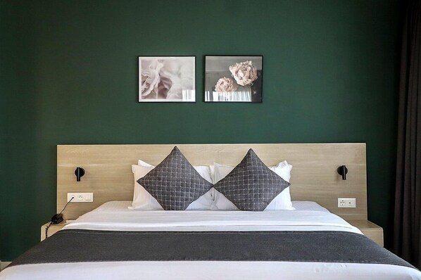 A neatly made bed with a wooden headboard, two pillows, and a dark throw blanket. - Ivotel Abidjan (Abidjan)