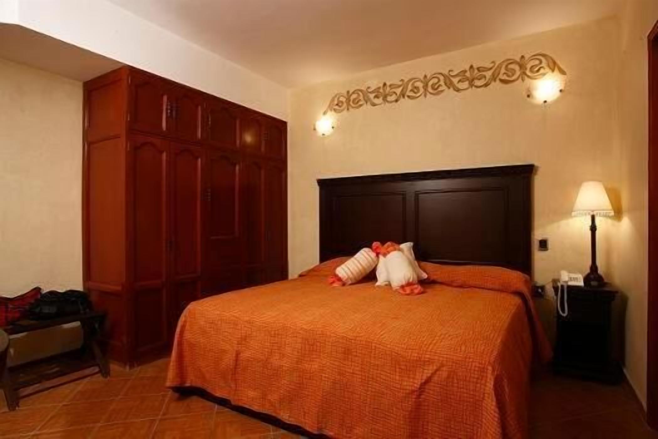 Een hotelkamer met een groot bed, een houten garderobe en een wandlamp.