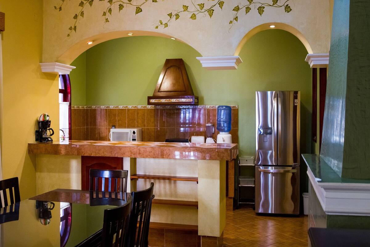 A kitchen with a central island, a stainless steel refrigerator, and a microwave.