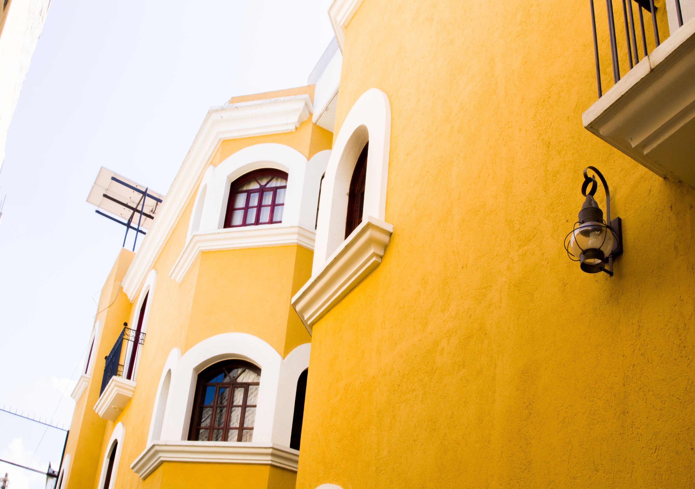Un bâtiment jaune avec des fenêtres en arc de cercle et un balcon.