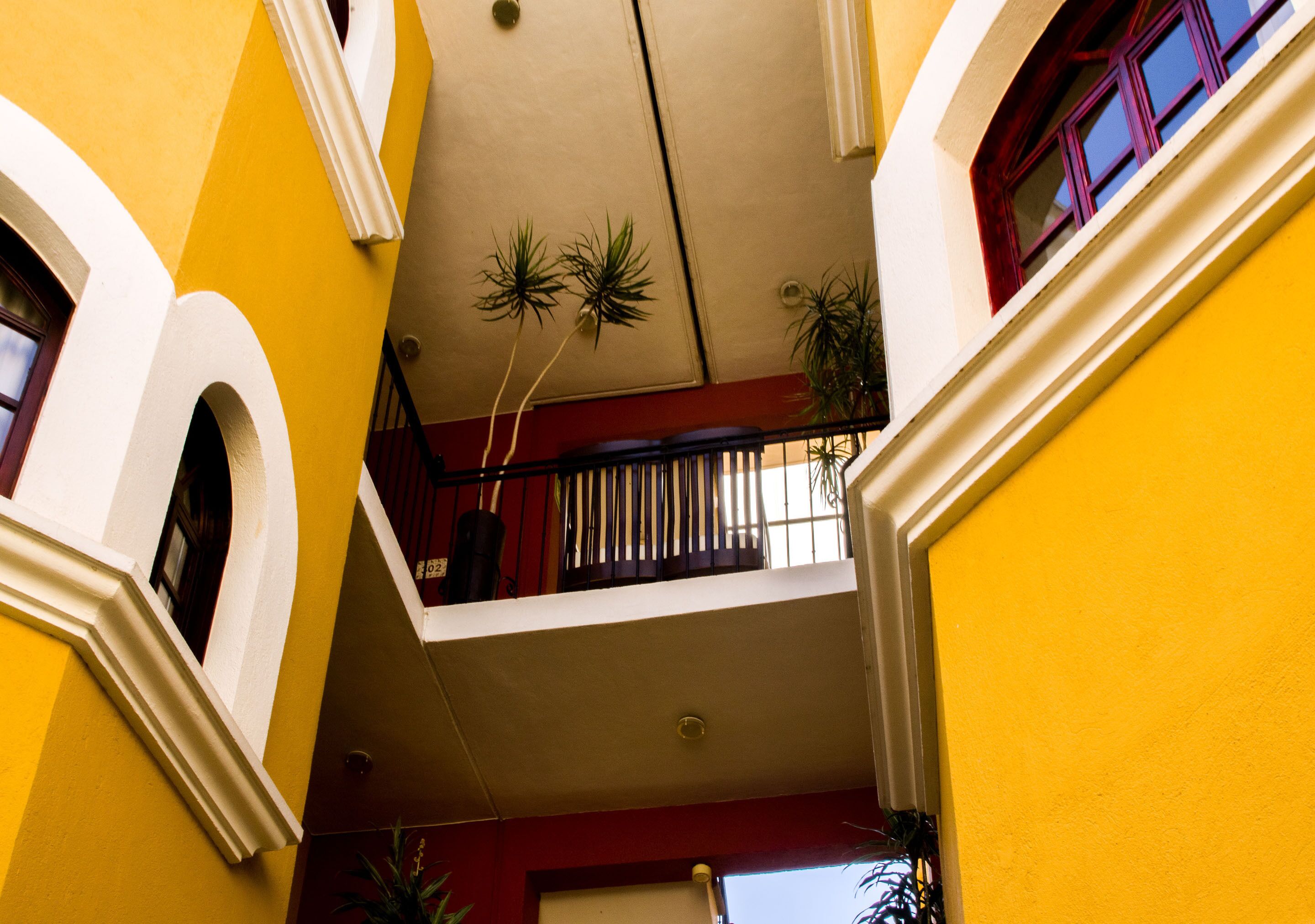 Ein mehrgeschossiges Interieur mit gelben Wänden, weißer Verzierung und einem Balkon mit Topfpflanzen.