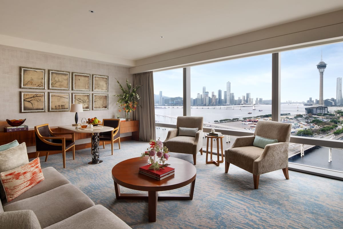 A modern hotel room with a large window offering a city skyline and water view.