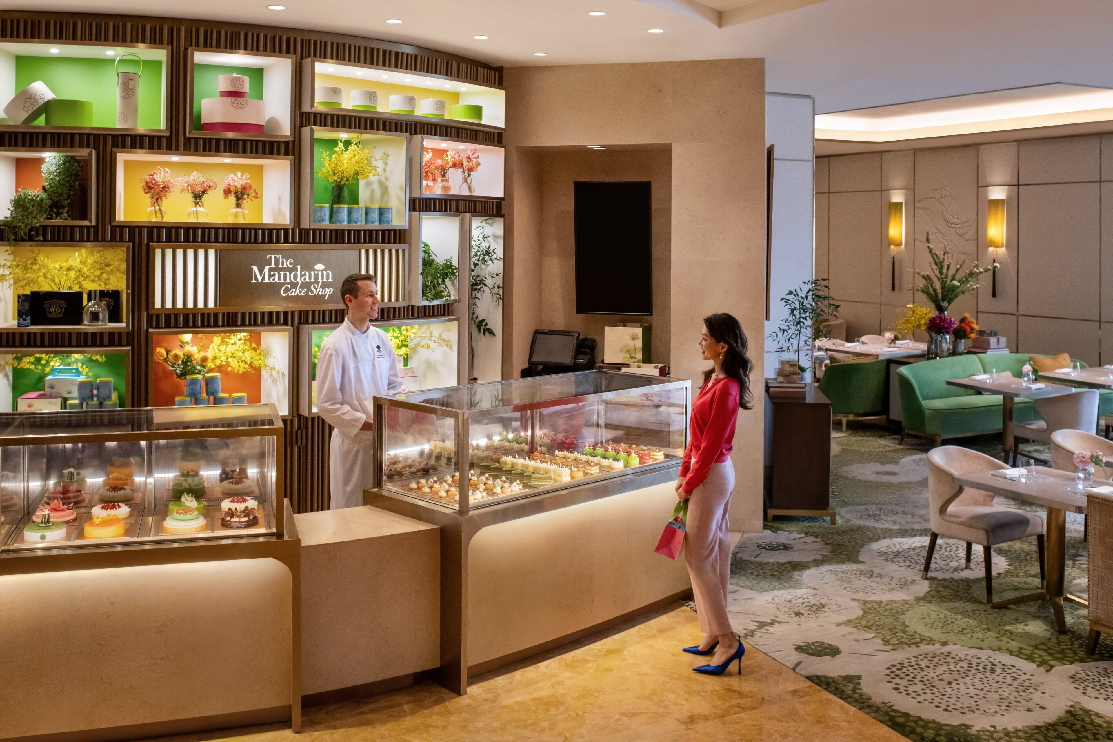 A hotel lobby with a cake display, seating area, and a reception desk.